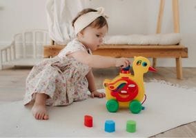 A pretty little baby girl plays alone with her duck toy. Melting Rainbow