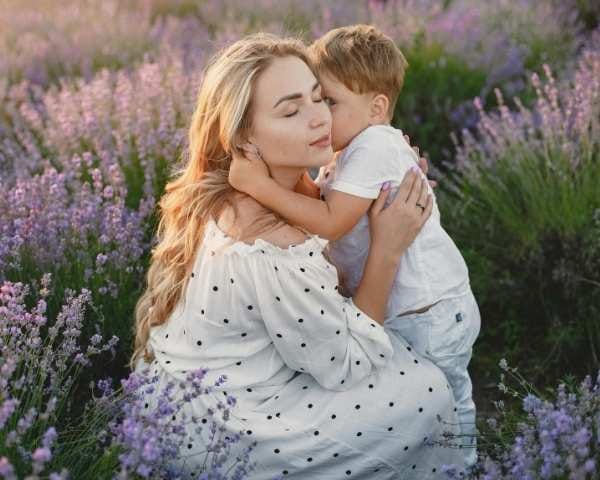 A baby boy hugs his mother and says mommy for the first time that feels his shy in the flower garden at afternoon
