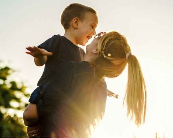 Toddler in mother’s arms with hands stretched sideways, showing bonding of parenting journey