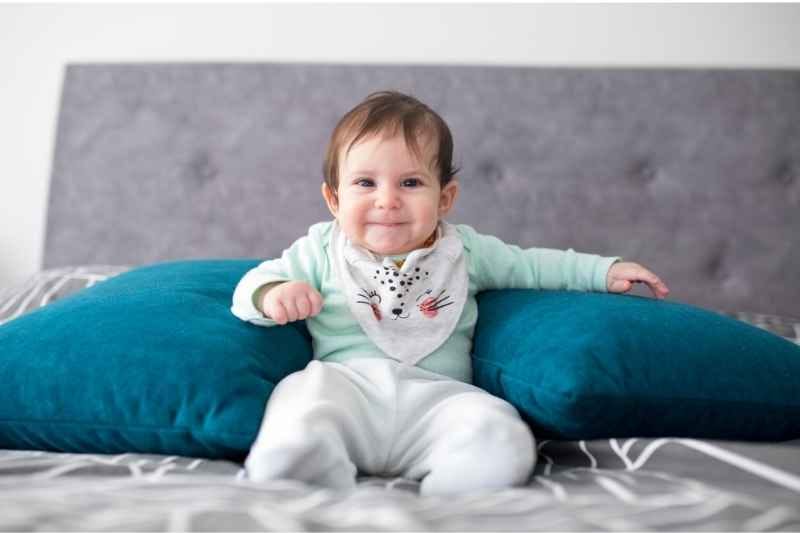 Five-month-old baby sitting with gentle support, showing early progress in balance, strength, and motor skill development.