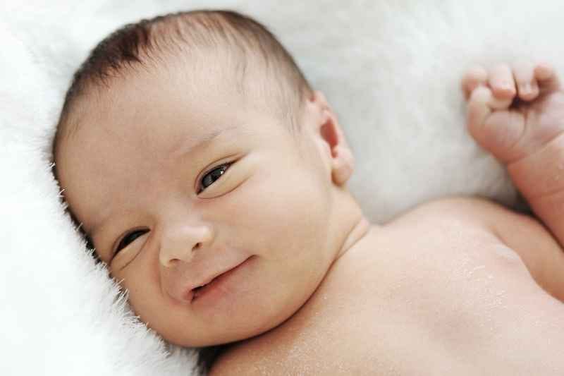 Two-month-old newborn showing the first sweet smile, marking a heartwarming milestone in early emotional development.