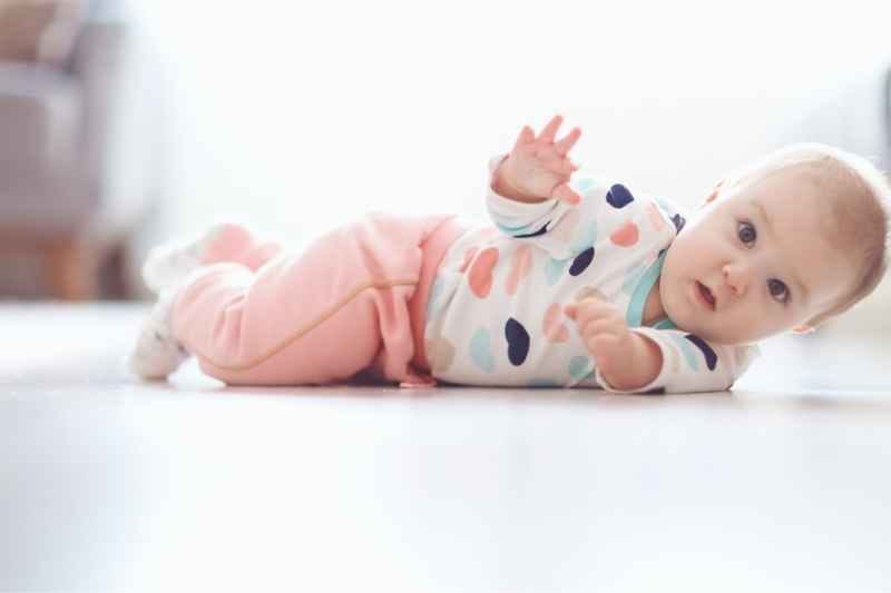 Four-month-old baby rolling over during tummy time, showing an exciting milestone in physical growth and motor skill development.