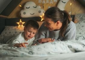 Mommy tells bedtime stories to her baby boy in the bed. And the bed decorates with soft lighting that creates dreamy land. Melting Rainbow