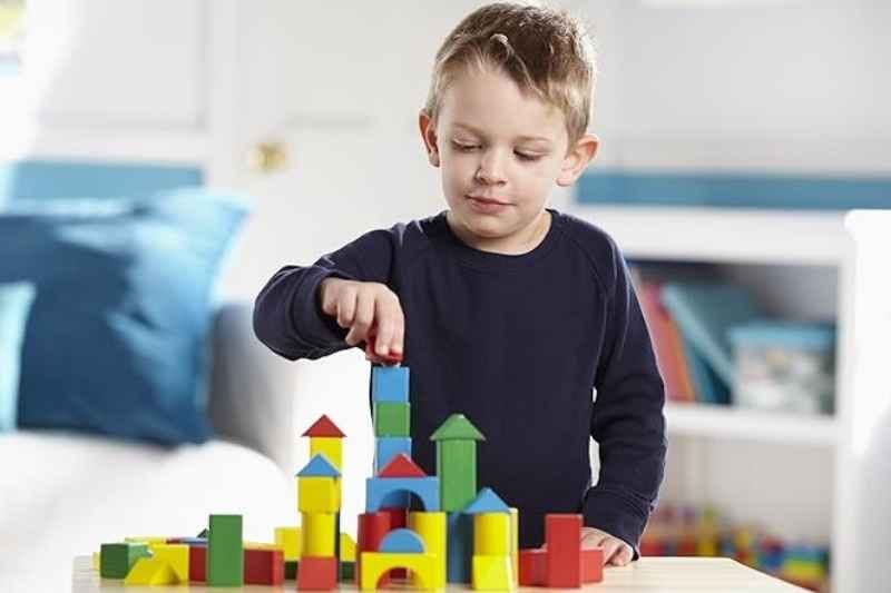 Toddler playing with Melissa & Doug Wooden Building Blocks 100-piece set — colorful stacking toy that supports child brain development through creative play.