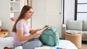 Cesarean Hospital Bag Checklist: pregnant woman in bed with a hospital bag and essential items, including a notebook for last-minute must-haves.