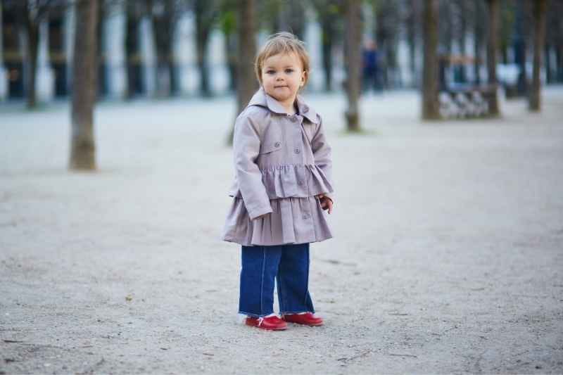 A toddler exploring a snowy trail during a nature walk, observing winter plants and animal tracks.