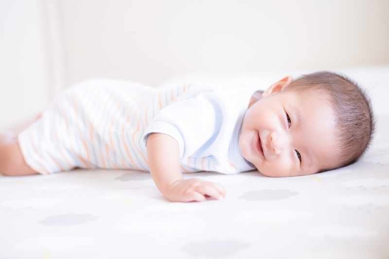 Baby showing mild resistance during supervised floor exercises, with a parent gently encouraging and supporting baby’s movements.