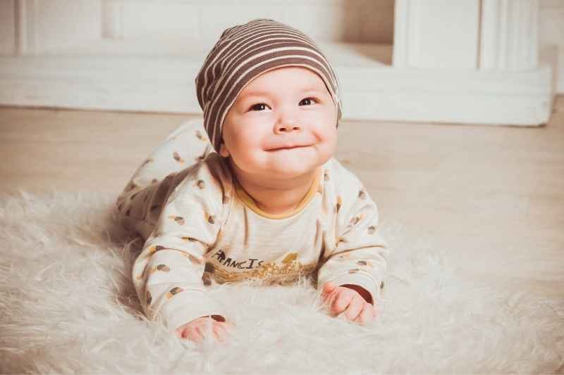 Newborn lying on a soft mat during supervised floor play, developing muscle strength and coordination through gentle exercises.